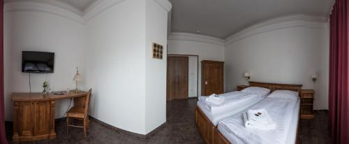 a bedroom with a bed with white sheets and a desk at Apartmány LAGUNA in Kopřivnice