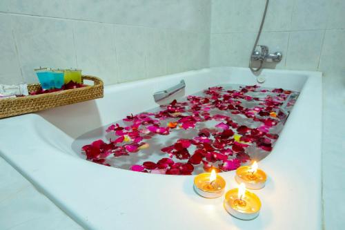 a bath tub filled with red flowers and candles at Thiha Bala Hotel in Pyin Oo Lwin