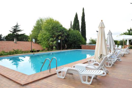 a swimming pool with lounge chairs and umbrellas at Villa Felcaro - Relais, Lodge & Restaurant in Cormòns