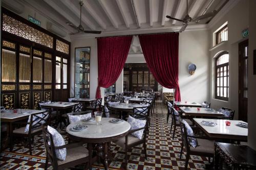 a restaurant with tables and chairs and red curtains at Seven Terraces in George Town
