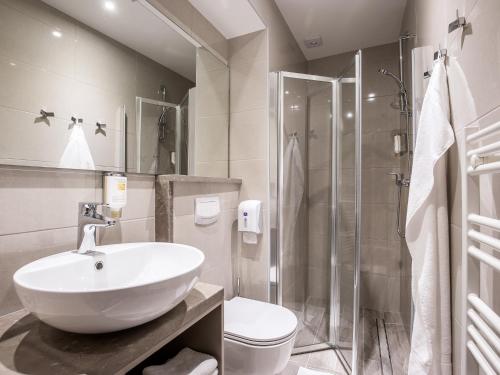 a bathroom with a sink and a toilet and a shower at Hotel Center Novo Mesto in Novo Mesto