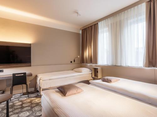 a hotel room with three beds and a tv at Hotel Center Novo Mesto in Novo Mesto