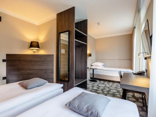 a hotel room with two beds and a desk at Hotel Center Novo Mesto in Novo Mesto