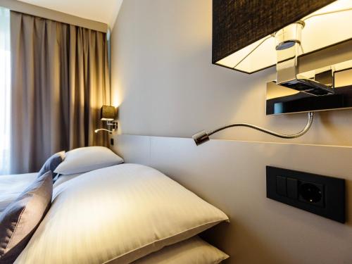 a hotel room with a bed and a lamp at Hotel Center Novo Mesto in Novo Mesto