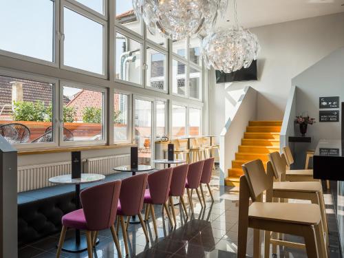 a restaurant with tables and chairs and windows at Hotel Center Novo Mesto in Novo Mesto