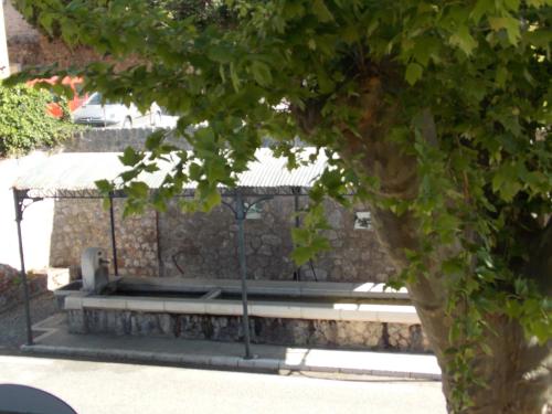a bench in a stone wall next to a tree at Au Relais Provencal in Bagnols-en-Forêt