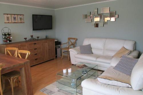 un salon avec un canapé blanc et une télévision dans l'établissement La Taniere Douce, à Soulaucourt-sur-Mouzon