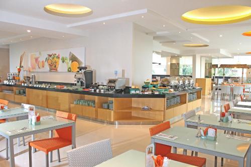 a restaurant with tables and chairs and a counter at HARRIS Hotel & Residences Riverview Kuta, Bali in Kuta
