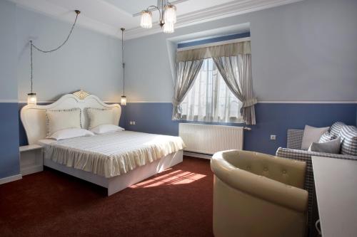 een slaapkamer met een bed, een bank en een stoel bij Green Palace Hotel in Shumen