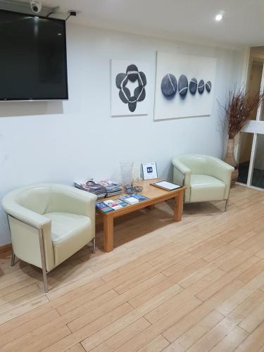 a living room with two chairs and a table and a tv at Travel Plaza Hotel in Desborough