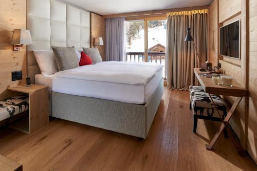 a bedroom with a bed and a desk and a television at Chandolin Boutique Hotel in Chandolin