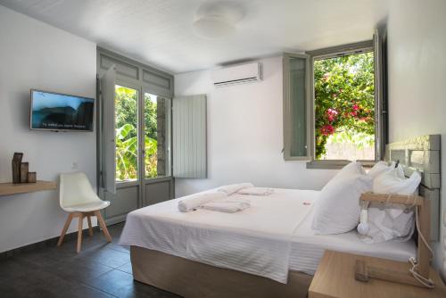 a bedroom with a white bed and two windows at Melagrana in Adamas