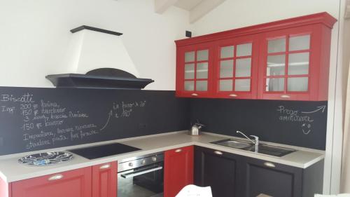 a kitchen with red and black cabinets and a sink at Rocca d'Anfo B&B-Apartments Lake View in Rocca dʼAnfo