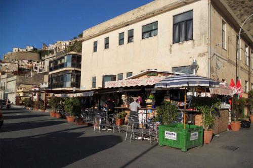 a building with chairs and an umbrella on a street at Villa Paladino - B&B e Guest House in Scilla
