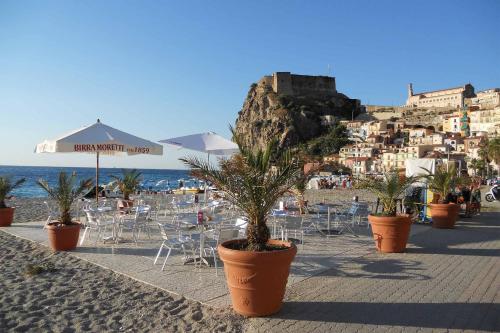 a beach with chairs and tables and a castle at Villa Paladino - B&B e Guest House in Scilla