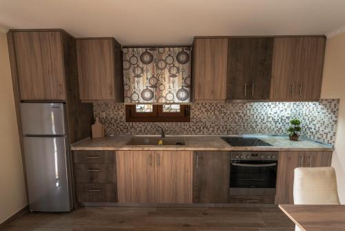 a kitchen with wooden cabinets and a stainless steel refrigerator at Dryades Apartments & Studios in Skala Potamias