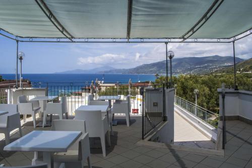 a patio with tables and chairs and a view of the ocean at Hotel Baia in Palinuro