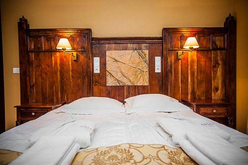 a large white bed with two lights on the wall at SPA Hotel Splendor in Lubenia
