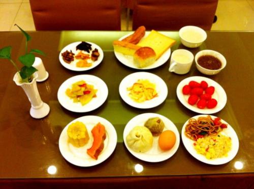 a table with plates of breakfast foods on it at GreenTree Inn Nanjing Yuhuatai Scenic Spot China Gate Subway Station Express Hotel in Nanjing