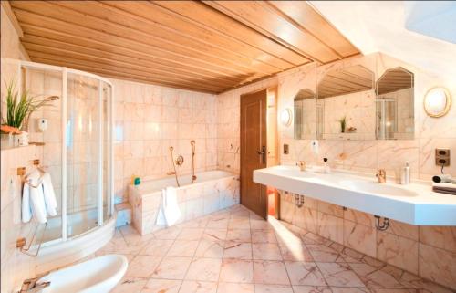 y baño con 2 lavabos, bañera y ducha. en Gasthof zum Weißen Lamm, en Sommerach