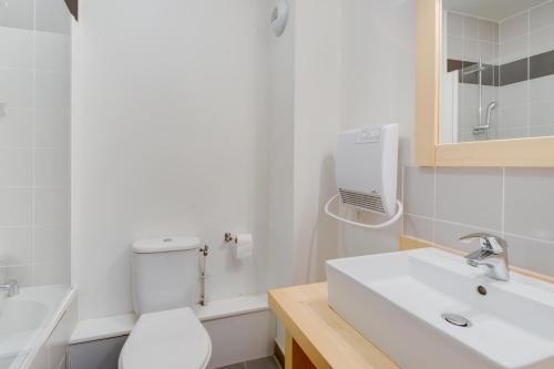 a white bathroom with a toilet and a sink at Vacancéole - Les Jardins de Balnéa in Loudenvielle
