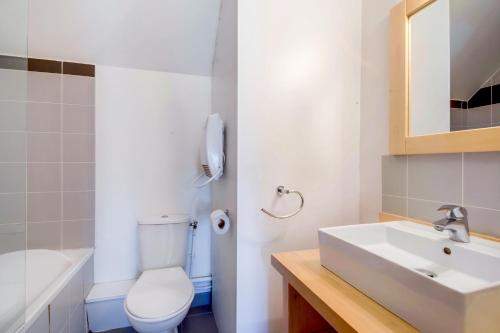a bathroom with a white toilet and a sink at Vacancéole - Les Jardins de Balnéa in Loudenvielle