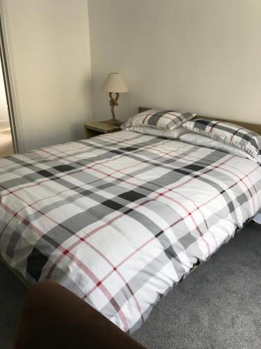 a bed with a plaid comforter on it in a bedroom at The Pier Hotel in Aberystwyth