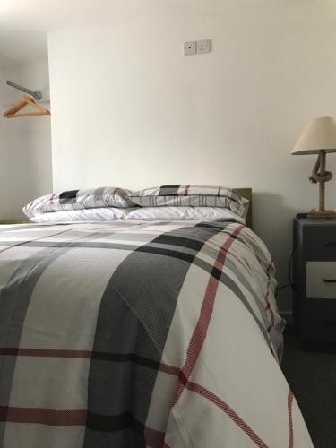 a bedroom with a bed with a striped blanket and a lamp at The Pier Hotel in Aberystwyth