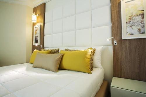a white bed with yellow pillows in a room at Sentido Bellevue Park in Port El Kantaoui