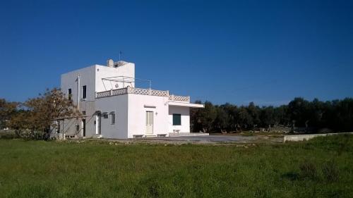 a white building sitting on top of a lush green field at Casa Vacanze Cisternella in Torre San Giovanni Ugento