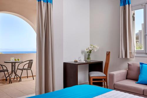 ein Schlafzimmer mit einem Bett, einem Sofa und einem Tisch in der Unterkunft Terra Blue Santorini in Kamari