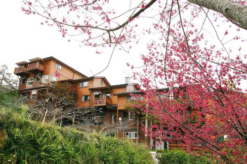 un bâtiment sur une colline avec des fleurs roses dans l'établissement Walk Cloud Bed and Breakfast, à Meishan