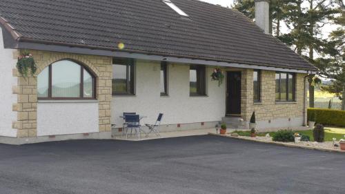 a white house with an arch and a chair in a driveway at Hillhaven Bed &Breakfast in Fortrose