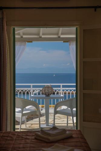 a bedroom with a view of the ocean from a balcony at Pension Votsi in Votsi