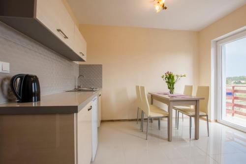a kitchen and dining room with a table and chairs at Apartamenty Maja -Pokoje - Domy wakacyjne -Basen Podgrzewany -Jacuzzi in Łeba
