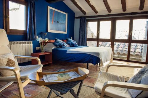 a blue bedroom with two beds and a chair at Lo Raconet de la Plaça in Calaceite