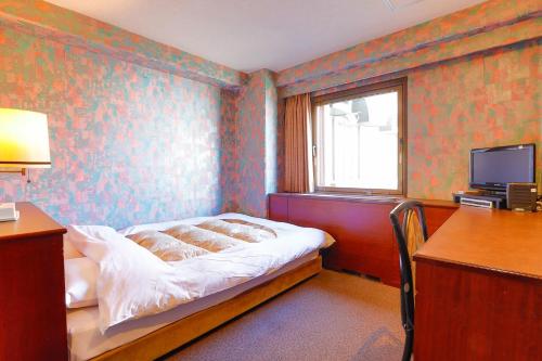 a bedroom with a bed and a desk and a television at Hotel Los Inn Kochi in Kochi
