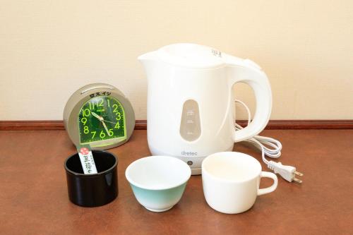 a tea kettle and cups and a clock on a table at Hotel Los Inn Kochi in Kochi