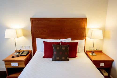 a bedroom with a bed with red pillows and two lamps at The Aberdeen Altens Hotel in Aberdeen