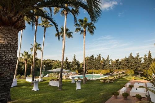 un complexe avec une piscine et des palmiers dans l'établissement Hotel Encinar de Sotogrande, à Sotogrande