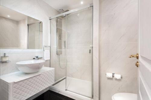 y baño blanco con lavabo y ducha. en Les Demoiselles à Versailles - Au Pied du Château, en Versalles