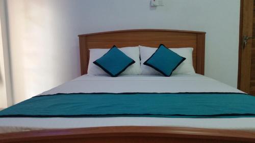 a bed with two blue pillows on top of it at Sunhill Lake Tourist Rest in Anuradhapura