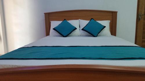 a bed with two blue pillows on top of it at Sunhill Lake Tourist Rest in Anuradhapura
