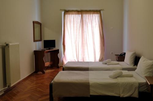 アテネにあるAchillion Apartmentのベッド2台と窓が備わる客室です。