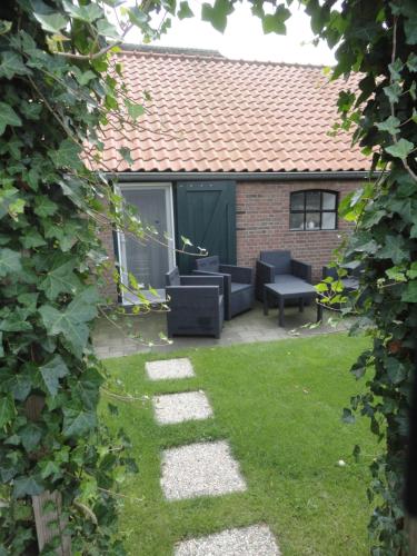 a backyard with a patio with chairs and a table at B&B De Willemshoeve in Wageningen