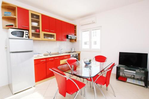una cucina con mobili rossi e un tavolo di vetro con sedie rosse di Villa Vrbat a Seget Vranjica