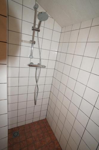 a white tiled shower with a shower head at De Wijde Verten in Oostkapelle