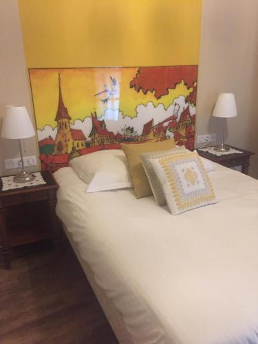 a bedroom with a white bed with a mural on the wall at Auberge Le Meisenberg in Châtenois