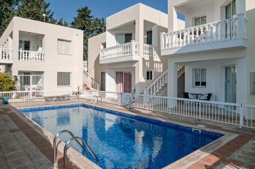 a villa with a swimming pool in front of a house at Sue's Apartment in Paphos