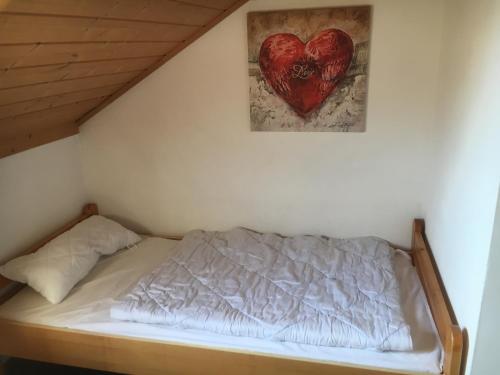 a bed with a heart hanging on the wall at Apartmentanlage am Kellerberg in Zandt